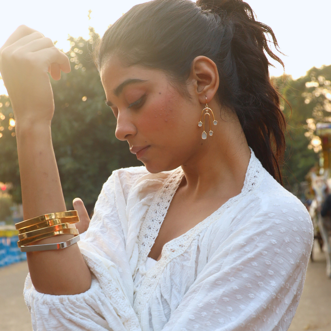 Model in playful cement earrings and square bangles