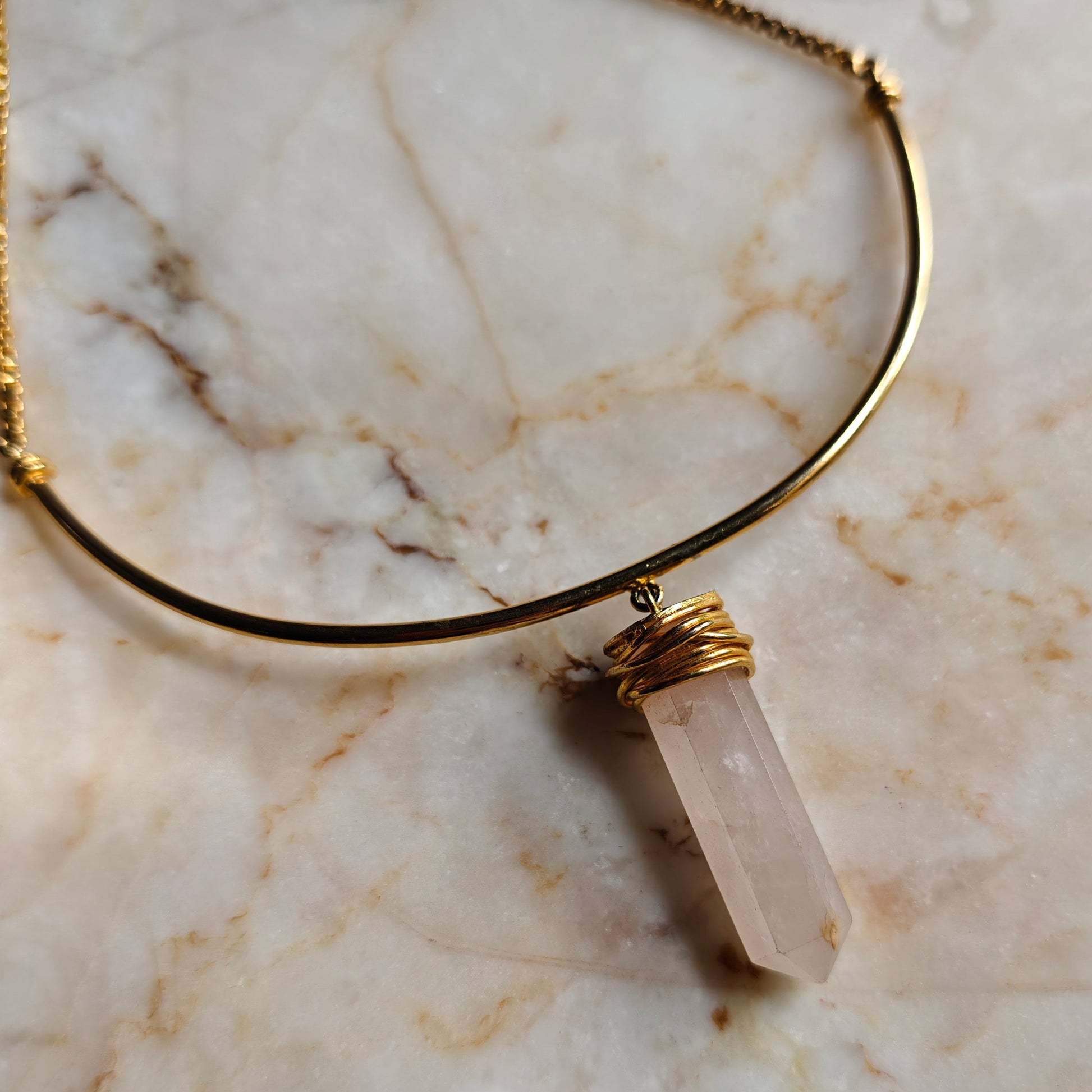 Necklace with a clear stone pendant on a marble surface