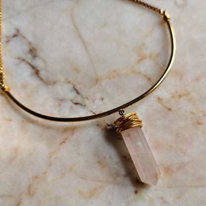 Necklace with a clear stone pendant on a marble surface
