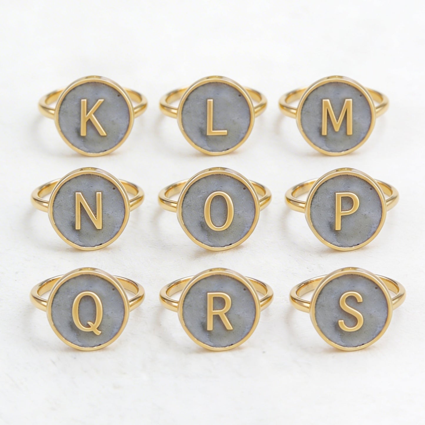 Set of gold and cement letter rings on a white background