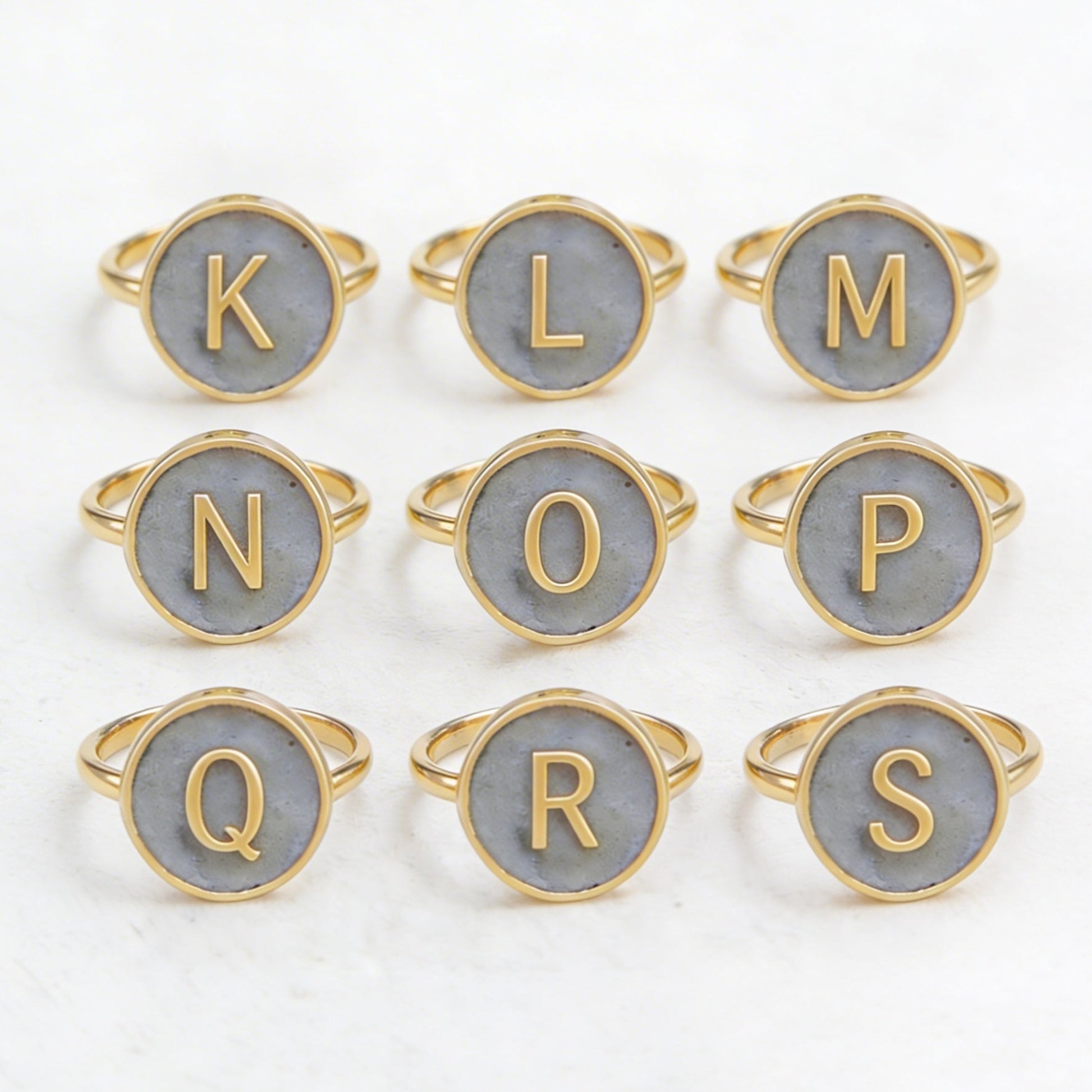Set of gold and cement letter rings on a white background