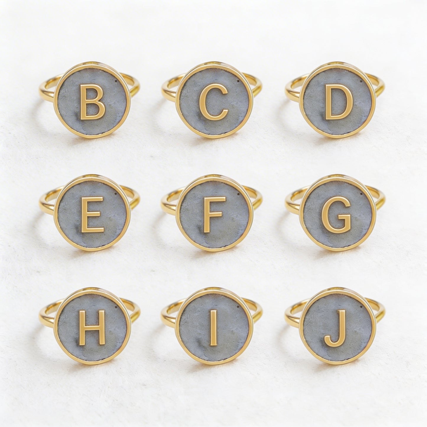 Set of gold and gray initial rings on a white background