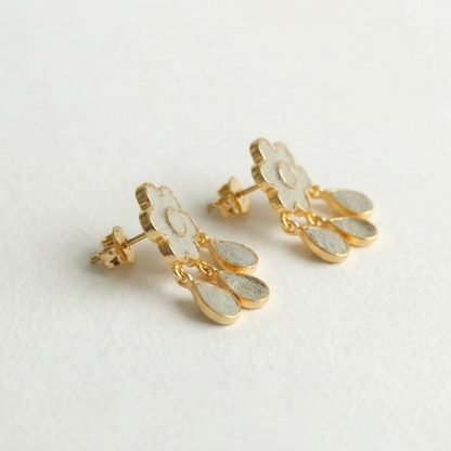 Gold and white earrings on a light gray background