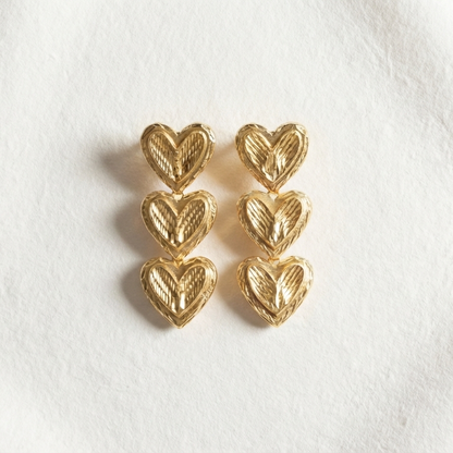 Pair of gold heart-shaped earrings on a white background