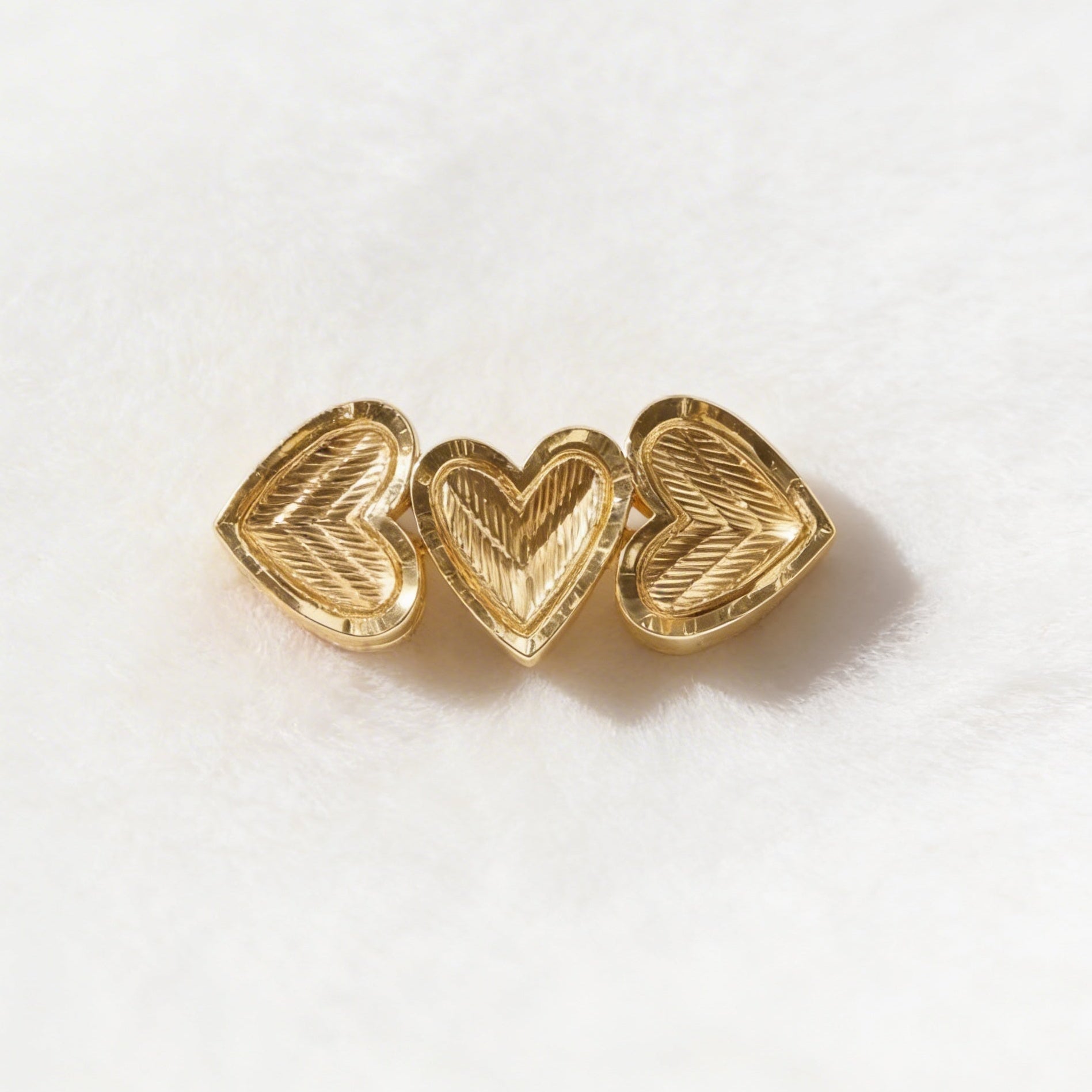 Gold heart-shaped earrings on a white background