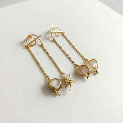 Angle view of semi-precious white druzy stone dangler earrings with a minimal gold chain design
